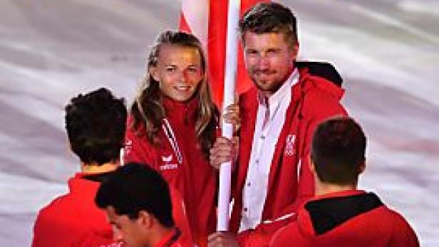 Zwei Sportler tragen die österreichische Flagge bei einer Olympiade.