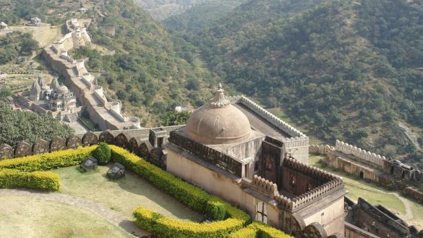 Blick auf die Festungsmauer von Kumbhalgarh, die sich durch die grüne Landschaft schlängelt.
