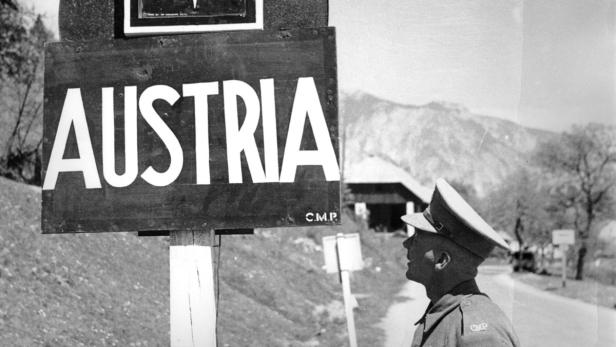 Ein Soldat steht an einer Grenzmarkierung mit der Aufschrift „Austria“.