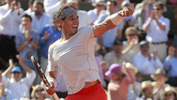 Rafael Nadal jubelt mit erhobener Faust und Tennisschläger vor einer applaudierenden Zuschauermenge.