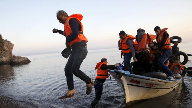 Menschen mit Schwimmwesten steigen von einem Boot ins Wasser.