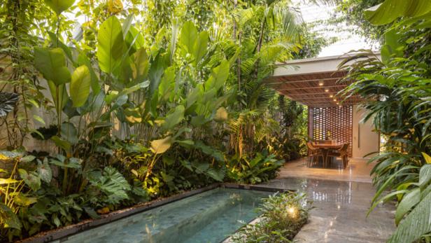 Ein kleiner Pool umgeben von tropischer Vegetation führt zu einem überdachten Essbereich.