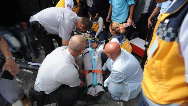 Sanitäter versorgen eine verletzte Person, die auf einer Trage liegt.