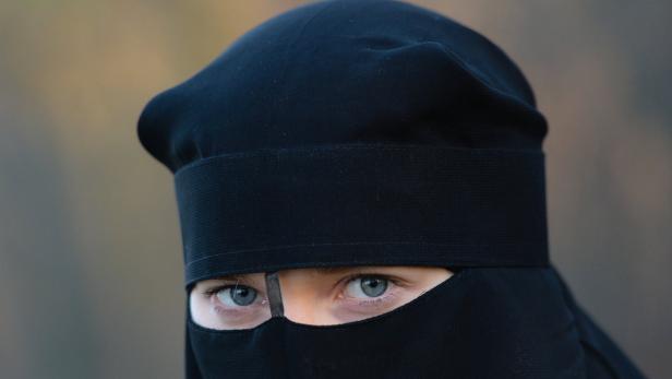 Eine Frau mit blauen Augen trägt einen schwarzen Niqab.