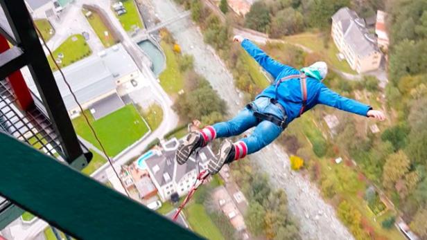 Eine Person springt mit einem Bungeeseil von einer hohen Brücke.