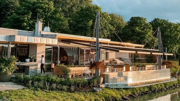 Ein modernes Gebäude mit Terrasse am Ufer eines Flusses.