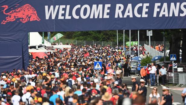 Große Menschenmenge unter einem „WELCOME RACE FANS“-Banner bei einer Motorsportveranstaltung.