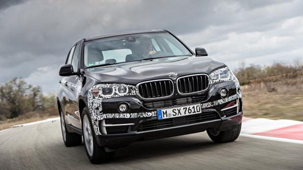 Ein schwarzer BMW mit Tarnmuster fährt auf einer Rennstrecke.