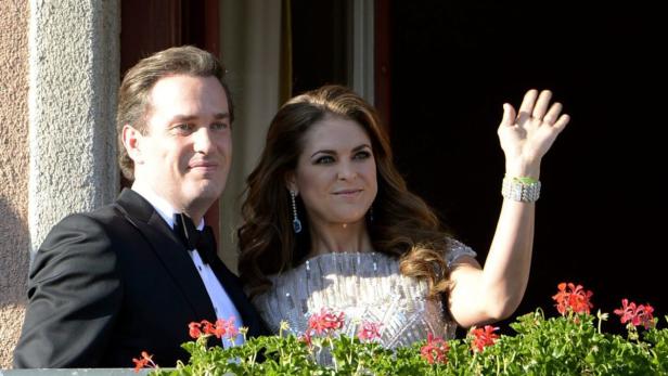Prinzessin Madeleine und Christopher O'Neill winken von einem Balkon.