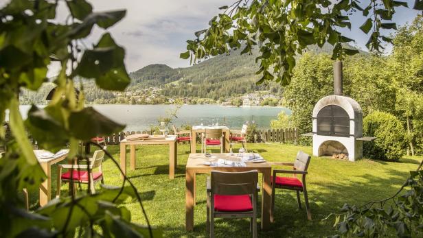 Ein Restaurantgarten mit Tischen und Stühlen am Ufer eines Sees.