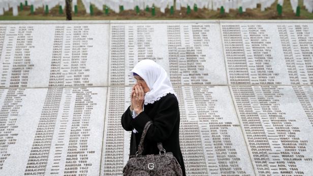 FILE PHOTO: A woman is seen near a grave of her family members in the Memorial centre Potocari, near Srebrenica