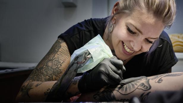 Stefanie Keuschnigg vom Dunkelbunt Tattoo Studio tätowiert einen Kunden.