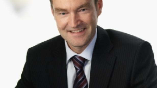 Ein lächelnder Mann im Anzug mit Krawatte.