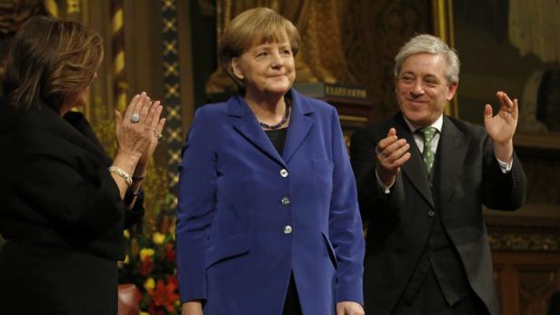 Angela Merkel wird von zwei Personen applaudiert.