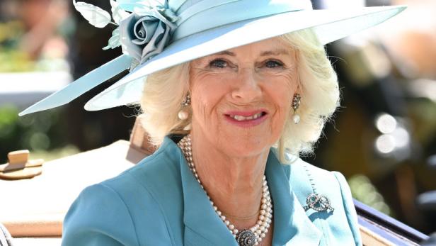 Königin Camilla trägt einen hellblauen Hut und eine passende Jacke.