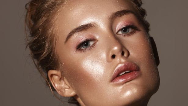 Porträt einer jungen Frau mit glänzendem Make-up und hochgesteckten Haaren.