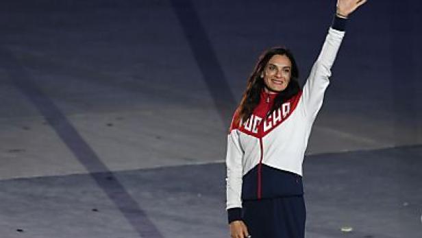 Eine Frau in Trainingskleidung winkt in die Menge.