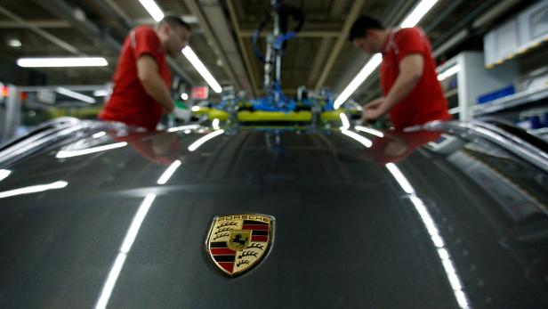 FILE PHOTO: Employees of German car manufacturer Porsche install the windshield of a Porsche 911 at the Porsche factory in Stuttgart-Zuffenhausen