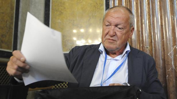 Ein Mann in einem Anzug betrachtet ein Blatt Papier.