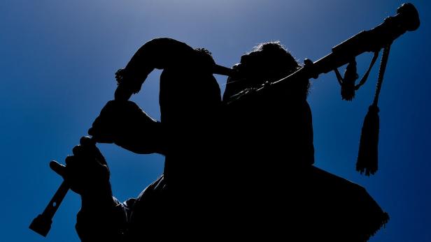 Die Silhouette eines Dudelsackspielers vor blauem Himmel.