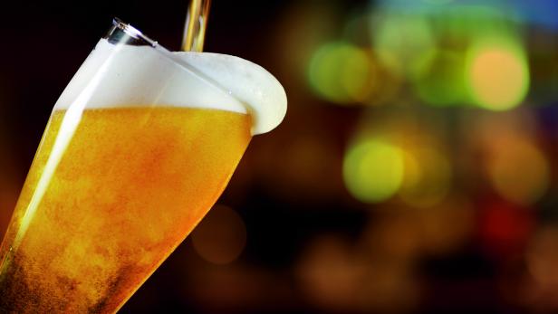 Ein Glas Bier wird eingeschenkt, mit Schaumkrone.