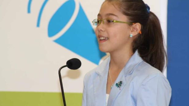 Ein junges Mädchen spricht bei einer Veranstaltung in ein Mikrofon.