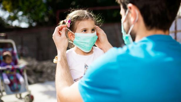 Single father applying pollution mask to his daughter