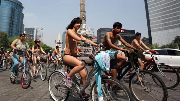 Mehrere Menschen nehmen an einer Nacktradfahrt in einer Stadt teil.