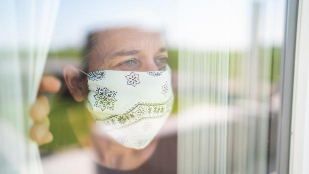 mature adult woman with mouse nose mask looking out through the window