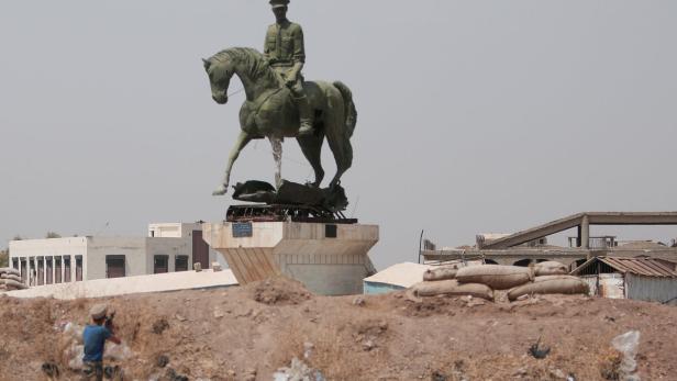 Hasaka: Ein kurdischer Kämpfer schießt auf eine Assad-Statue.
