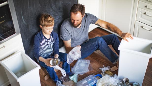 Mülltrennung: Vater und Sohn sortieren Abfälle zu Hause.