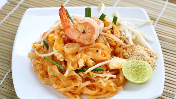 Ein Teller Pad Thai mit Garnelen, Sprossen, Limette und Erdnüssen.