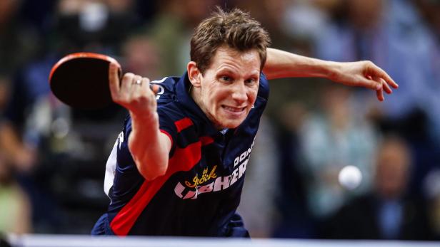 Ein Tischtennisspieler schlägt den Ball mit seinem Schläger.