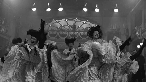 Eine Gruppe von Tänzerinnen führt einen Cancan auf einer Bühne auf.