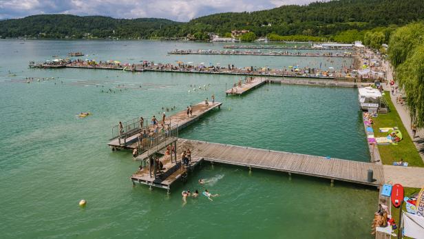 Ein belebtes Strandbad mit Badegästen auf Stegen und im türkisfarbenen Wasser.