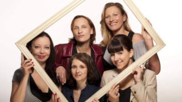 Fünf Frauen posieren zusammen und halten einen leeren Bilderrahmen.