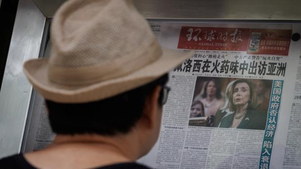 A man reads a newspaper that features an article about U.S. House of Representatives Speaker Nancy Pelosi's Asia tour, in Beijing