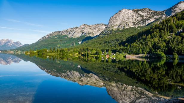 Der Altausseer See spiegelt die umliegenden Berge und den klaren blauen Himmel wider.