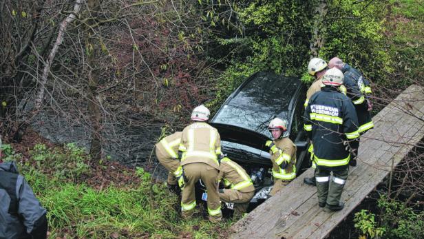 Ein Auto ist in einen Bach gestürzt und wird von Feuerwehrleuten geborgen.