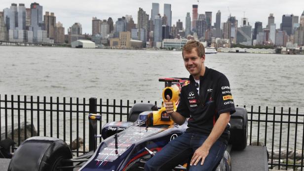 Sebastian Vettel posiert vor einem Formel-1-Wagen mit der Skyline von New York im Hintergrund.