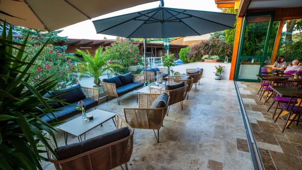 Einladende Terrasse mit Korbmöbeln und üppiger Bepflanzung.