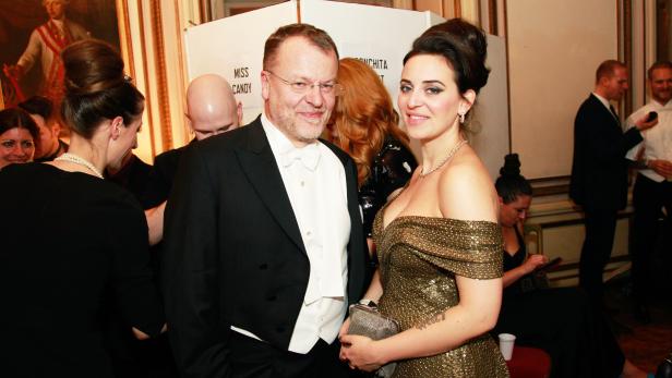 Ein Mann im Smoking und eine Frau im goldenen Kleid posieren für ein Foto.