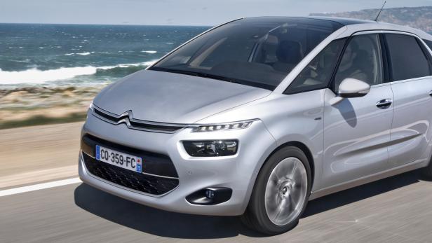 Ein silberner Citroën fährt auf einer Küstenstraße.
