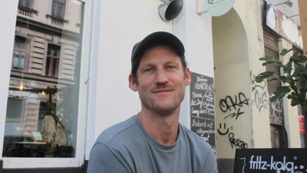 Ein Mann mit Kappe sitzt vor dem Imbiss „EH Wurst“.