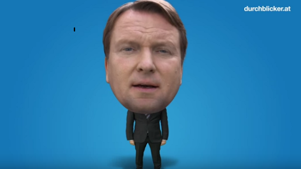 Ein Mann mit übergroßem Kopf in einem Anzug vor blauem Hintergrund.