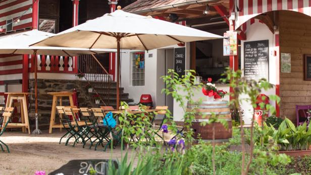 Einladender Außenbereich eines Cafés mit Tischen, Stühlen und Sonnenschirmen.