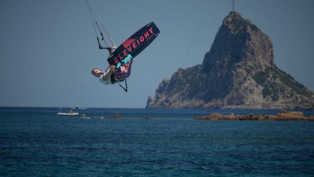 Ein Kitesurfer macht einen Trick in der Luft über dem Meer.