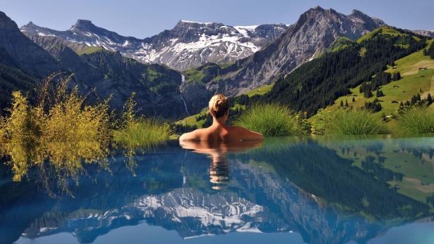Eine Frau genießt die Aussicht auf die schneebedeckten Berge von einem Pool aus.