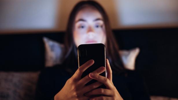 Eine junge Frau schaut auf ihr Handy.