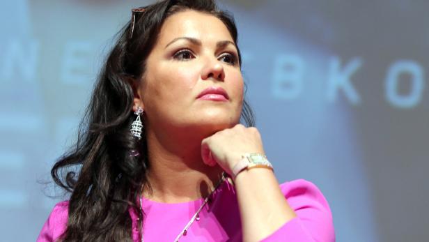Anna Netrebko posiert mit der Hand am Kinn.